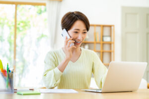 松戸市_パソコン見ながら電話相談している女性